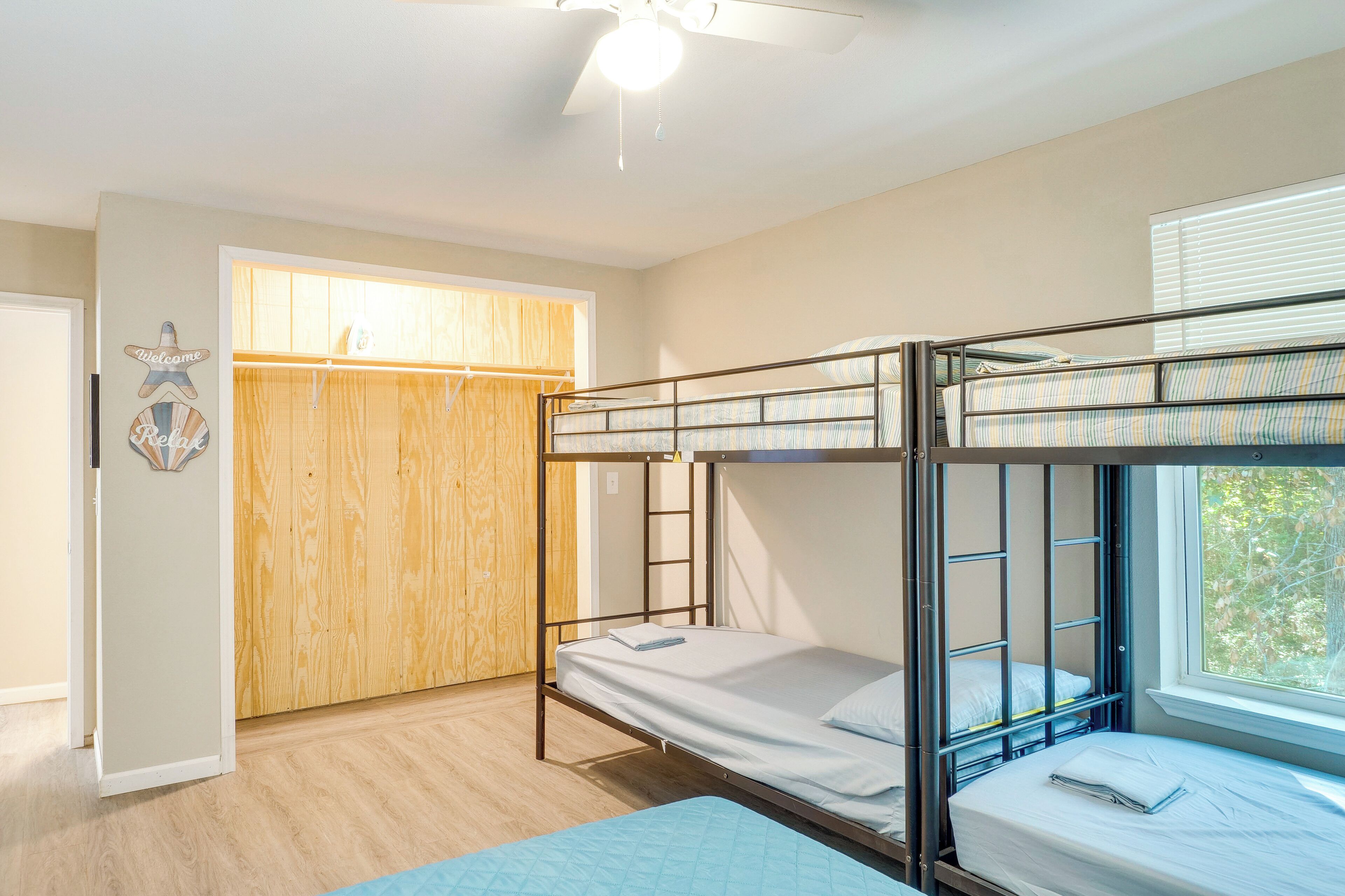 A bunk bed room with a wooden wardrobe, a ladder, and a window with blinds.