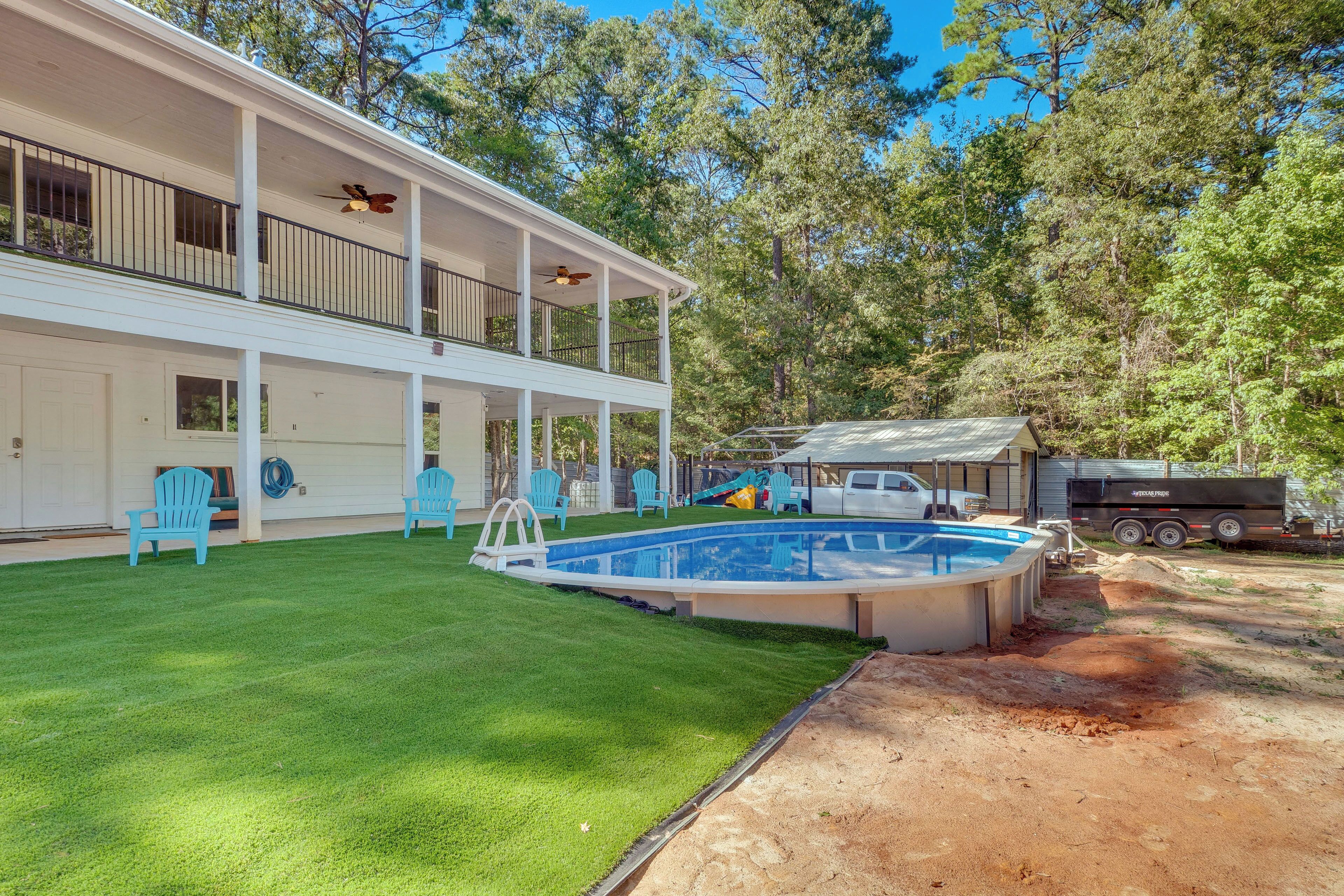 A two-story house with a covered patio, a swimming pool, and a dirt area.