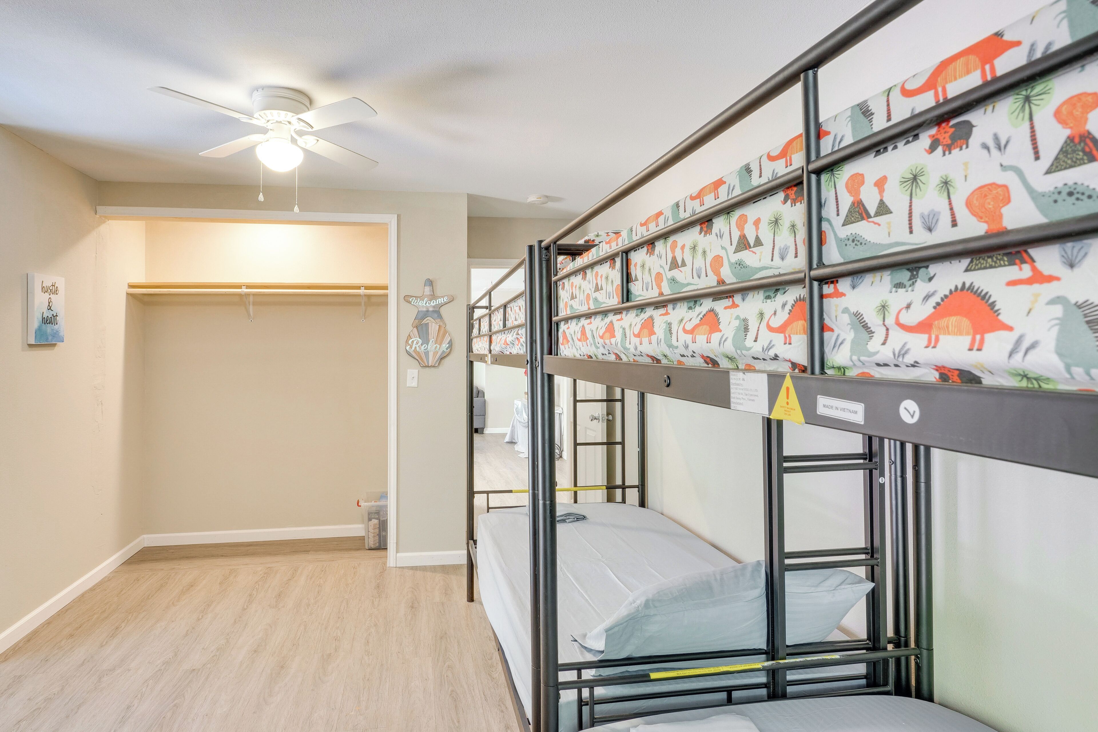 Ein Schlafraum mit Etagenbetten, Deckenventilator, Kleiderschrank und einer Willkommensanzeige.