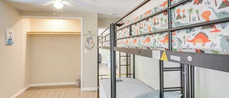 Ein Schlafraum mit Etagenbetten, Deckenventilator, Kleiderschrank und einer Willkommensanzeige.
