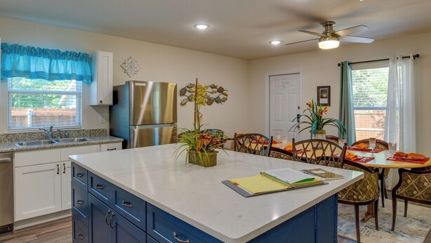 A modern kitchen with a central island, built-in appliances, and a dining area with a table and chairs. - Game Room + Walk to Beach: Gun Barrel City Gem! (Mabank)