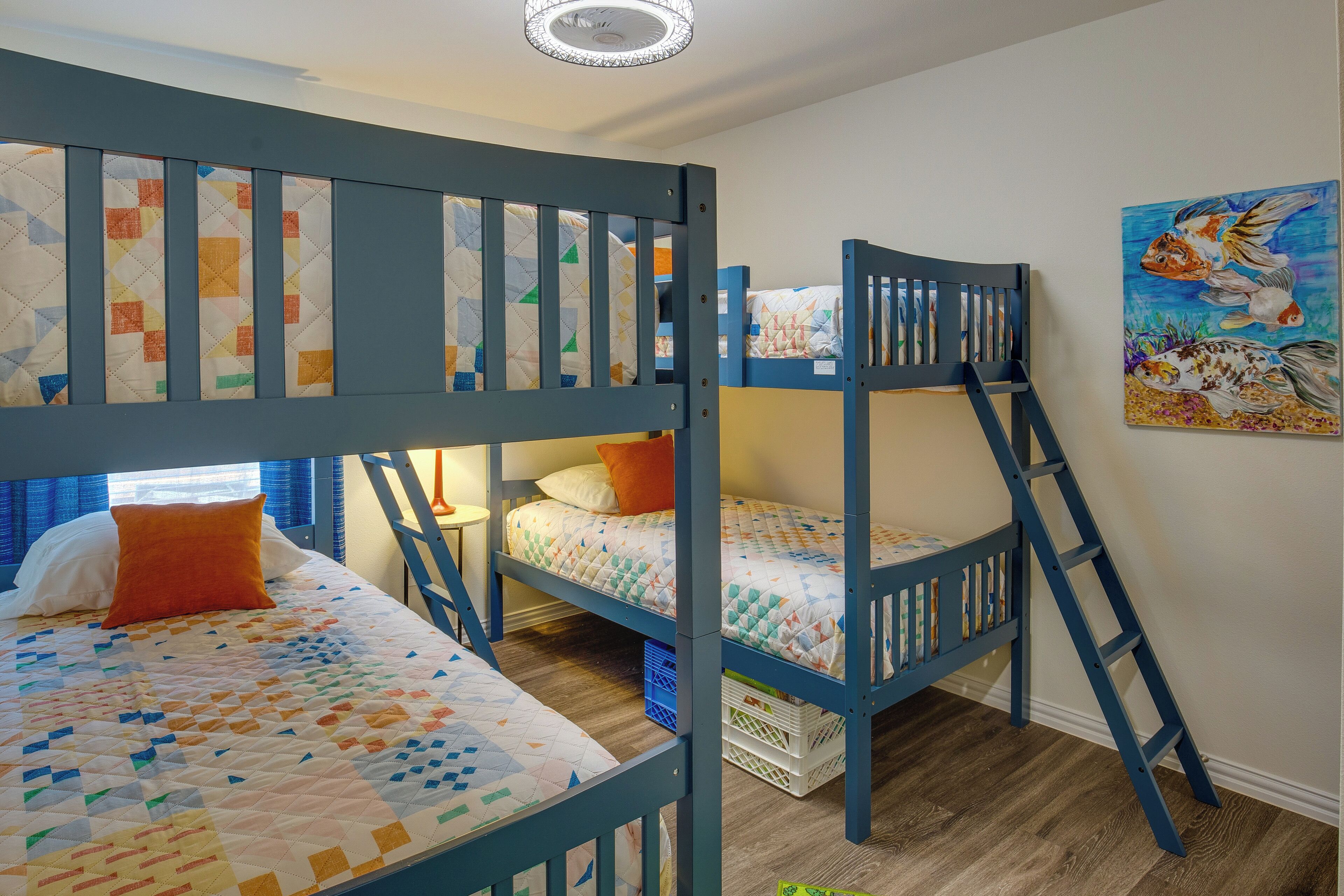Een slaapkamer met een stapelbed, een gewatteerd sprei en een schilderij aan de muur.