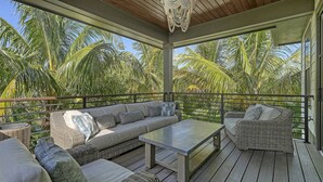 Eine überdachte Terrasse im Freien mit einer Couch, Sesseln und einem Tisch.