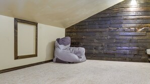 A room with a sloped ceiling, a wooden wall panel, a framed picture, and a bean bag chair. - Family-friendly Utah Home: Deck, Mountain Views! (Vernal)