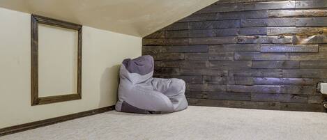 A room with a sloped ceiling, a wooden wall panel, a framed picture, and a bean bag chair.