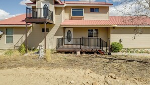 A two-story house with a red roof, a balcony on the upper floor, and a front porch with a railing. - Family-friendly Utah Home: Deck, Mountain Views! (Vernal)