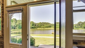 A view through a glass door of a lake, a grassy area, and a stone wall. - Waterfront Benson Retreat: Rescue Farm w/ a Lake! (Benson)