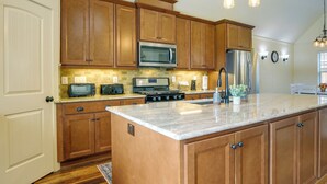 A kitchen with wooden cabinets, a stainless steel microwave, a refrigerator, and a granite countertop. - Waterfront Benson Retreat: Rescue Farm w/ a Lake! (Benson)