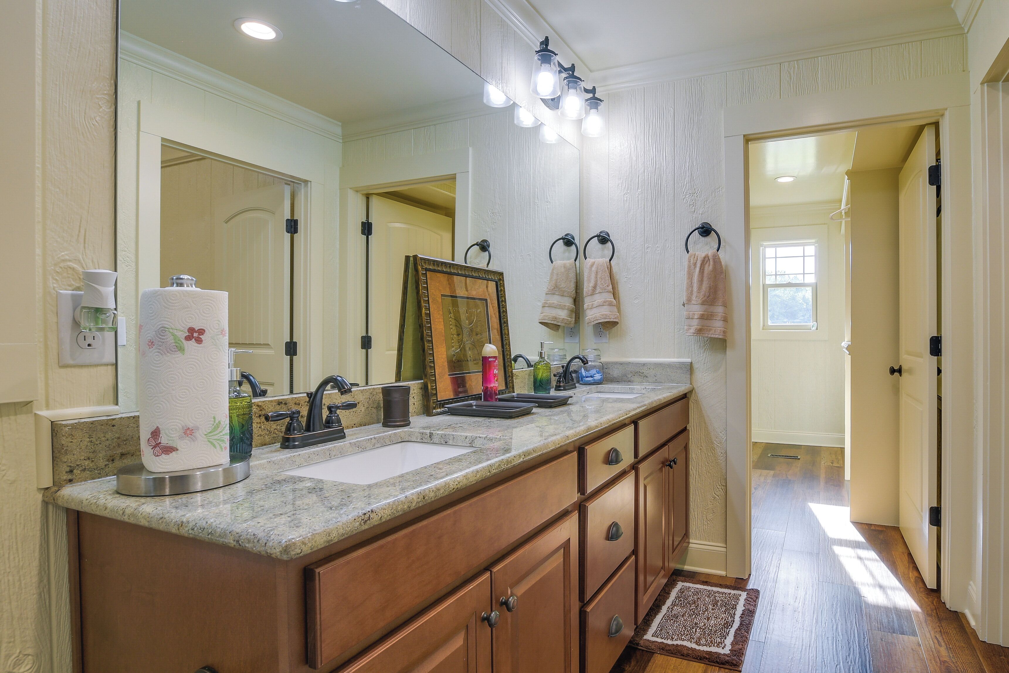A bathroom with a double sink vanity, a large mirror, and a framed picture above the mirror.