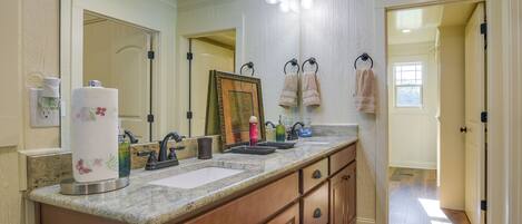 A bathroom with a double sink vanity, a large mirror, and a framed picture above the mirror.