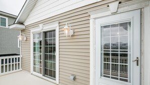 A house with a covered porch, a sliding glass door, and a white door with a window.