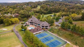 A large building with a tennis court and a swimming pool.
