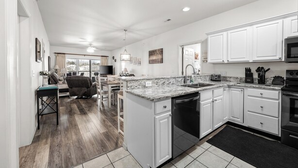 A spacious kitchen with white cabinets, a granite countertop, and a dishwasher.