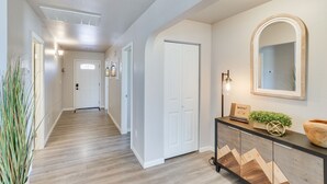 A hallway with wooden flooring, white walls, and a wooden console table with a mirror and decorative items. - Gold Canyon Vacation w/ Private Patio & Fire Pit! (Gold Canyon)