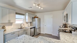 A modern kitchen with white cabinets, granite countertops, stainless steel appliances, and a window with blinds. - Gold Canyon Vacation w/ Private Patio & Fire Pit! (Gold Canyon)
