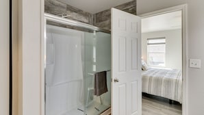 A bedroom with a bed, a glass shower enclosure, and a white door leading to another room. - Gold Canyon Vacation w/ Private Patio & Fire Pit! (Gold Canyon)