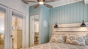 A bedroom with a wooden headboard, a patterned bedspread, and a ceiling fan. - Villa & Garden in Downtown Sarasota ~ Walkable to downtown, 5 Minutes to Beaches (Sarasota)