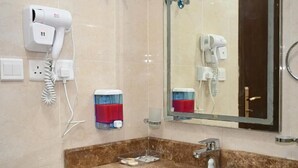 A bathroom with a sink, mirror, hairdryer, and towel dispenser. - SALSBIL AL ALMASI HOTEL (Madinah)