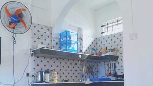A kitchen with a microwave, a fan, and a blue shelf unit. - Relax and Unwind at our Stunning Vacation Rental in Pointe aux Biches, Mauritius (Pointe Aux Piments)