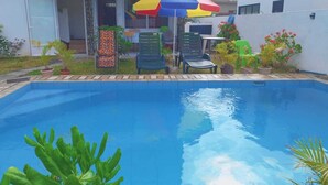 A swimming pool with a tiled edge, surrounded by potted plants and outdoor furniture. - Relax and Unwind at our Stunning Vacation Rental in Pointe aux Biches, Mauritius (Pointe Aux Piments)