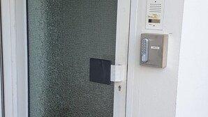 Une porte dotée d’un panneau en verre texturé, d’un clavier pour ouvrir la porte et d’un système d’interphone numérique.