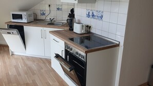 Une cuisine moderne avec des meubles blancs, un four à micro-ondes, un grille-pain et un lave-vaisselle.