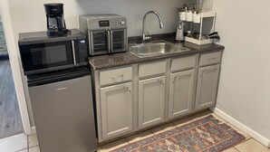 A compact kitchen with a microwave, toaster, sink, and coffee maker. - South Lake Charles Guest Cottage - Country Setting, Rustic Ambience (Lake Charles)