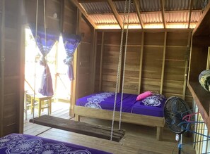 A wooden room with a bed, a swing, and a fan.