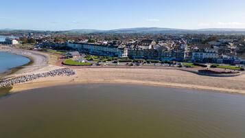 An aerial view of a coastal town with a sandy beach, residential buildings, and a large body of water.