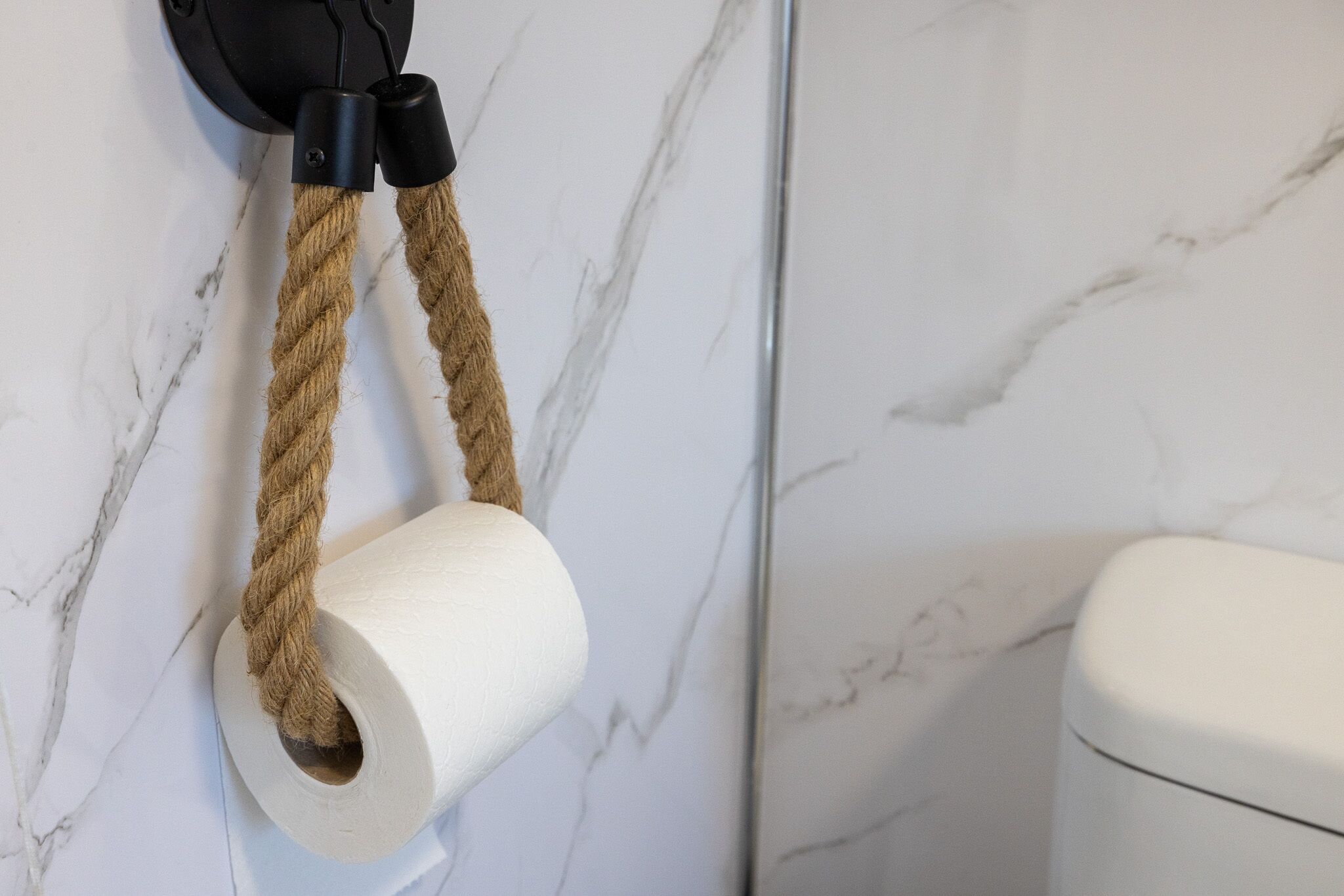 A toilet paper roll mounted on a wall with marble patterns.