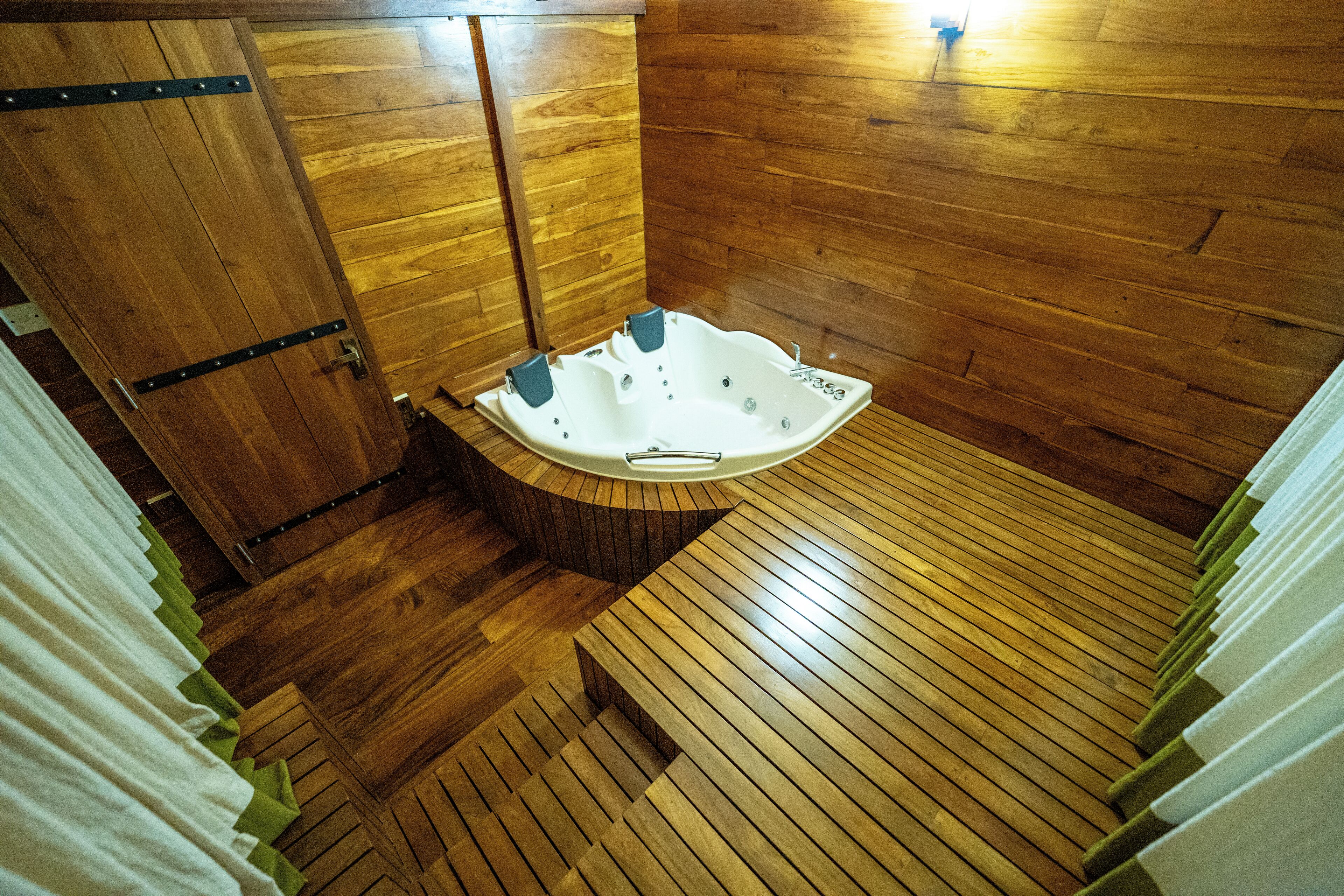 A wooden-floored bathroom with a freestanding bathtub and a wooden bench.