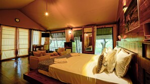Un dormitorio amplio con una cama grande, una zona de estar con sofá y sillones, y un televisor.