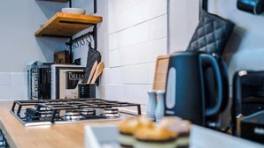 A kitchen with a gas stove, a coffee maker, and a plate of food.