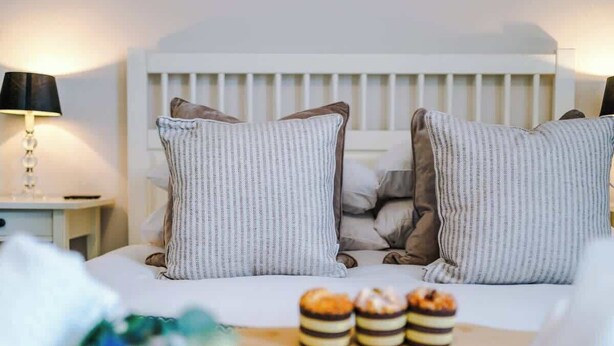 A bedroom with a white crib, striped pillows, and a tray with layered desserts.