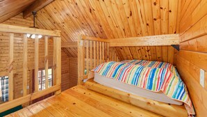 Een houten kamer met een stapelbed, een raam en een houten plafond.