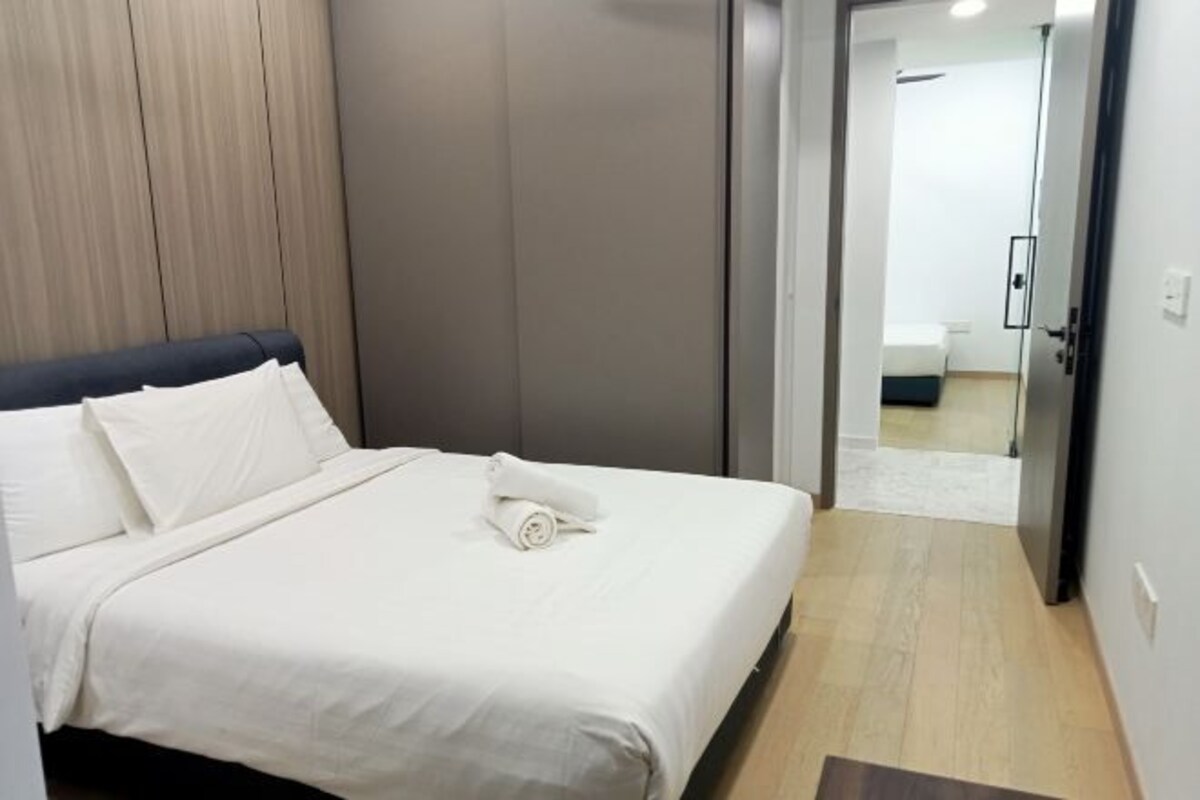 A hotel room with a neatly made bed, a wooden headboard, and a view into the bathroom through an open door.