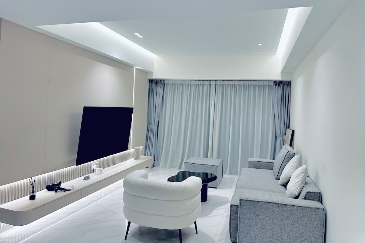 A modern living room with a sofa, a coffee table, a TV, and a built-in bench with storage.