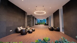 A modern lobby with a wooden floor, seating areas, and a view of greenery. - Eaton Residences KLCC by Luna (Kuala Lumpur)