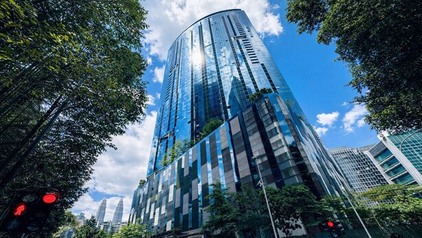 A high-rise building with a glass facade, surrounded by trees and other buildings. - Eaton Residences KLCC by Luna (Kuala Lumpur)