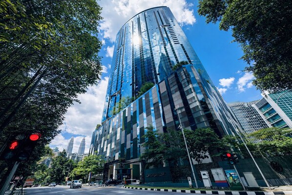 Ein Hochhaus mit Glasfassade, umgeben von Bäumen und anderen Gebäuden.