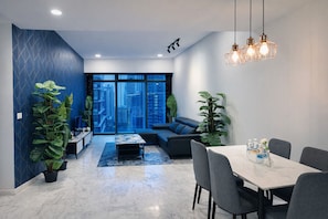 Een moderne woonkamer met een bank, een eettafel met stoelen en grote ramen met uitzicht op de stad.