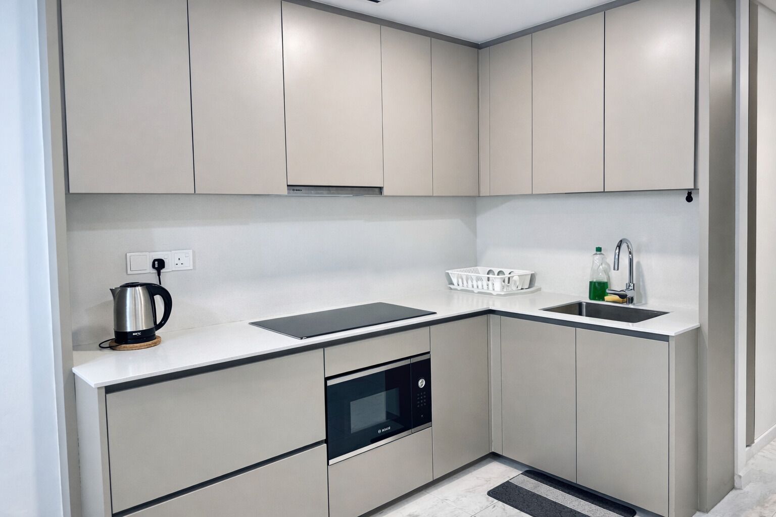 A modern kitchen with built-in appliances, a sink, and a kettle.