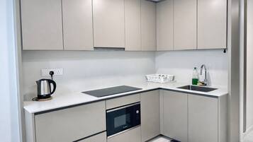 A modern kitchen with built-in appliances, a sink, and a kettle.