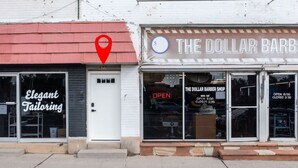 Una botiga amb un cartell que diu 'The Dollar Barber Shop' i un altre cartell que anuncia 'Elegant Tailoring'.