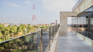 A modern building with a glass facade overlooking a park and distant cityscape. - Al-Istiklal Suites (Ramallah)