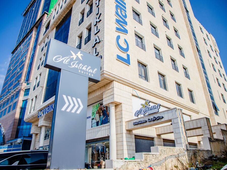 A hotel with a sign for 'Al Islah Suites' and 'LC Walkal' on the facade.