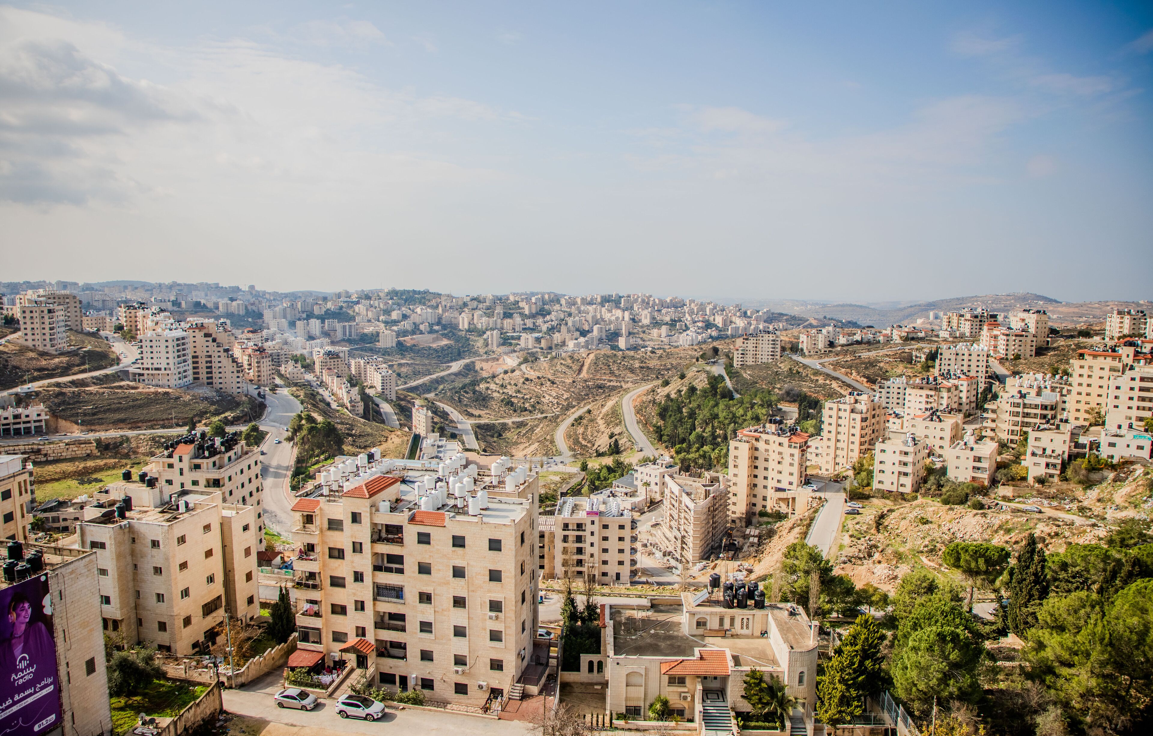 A cityscape with residential buildings, roads, and a hilly terrain.