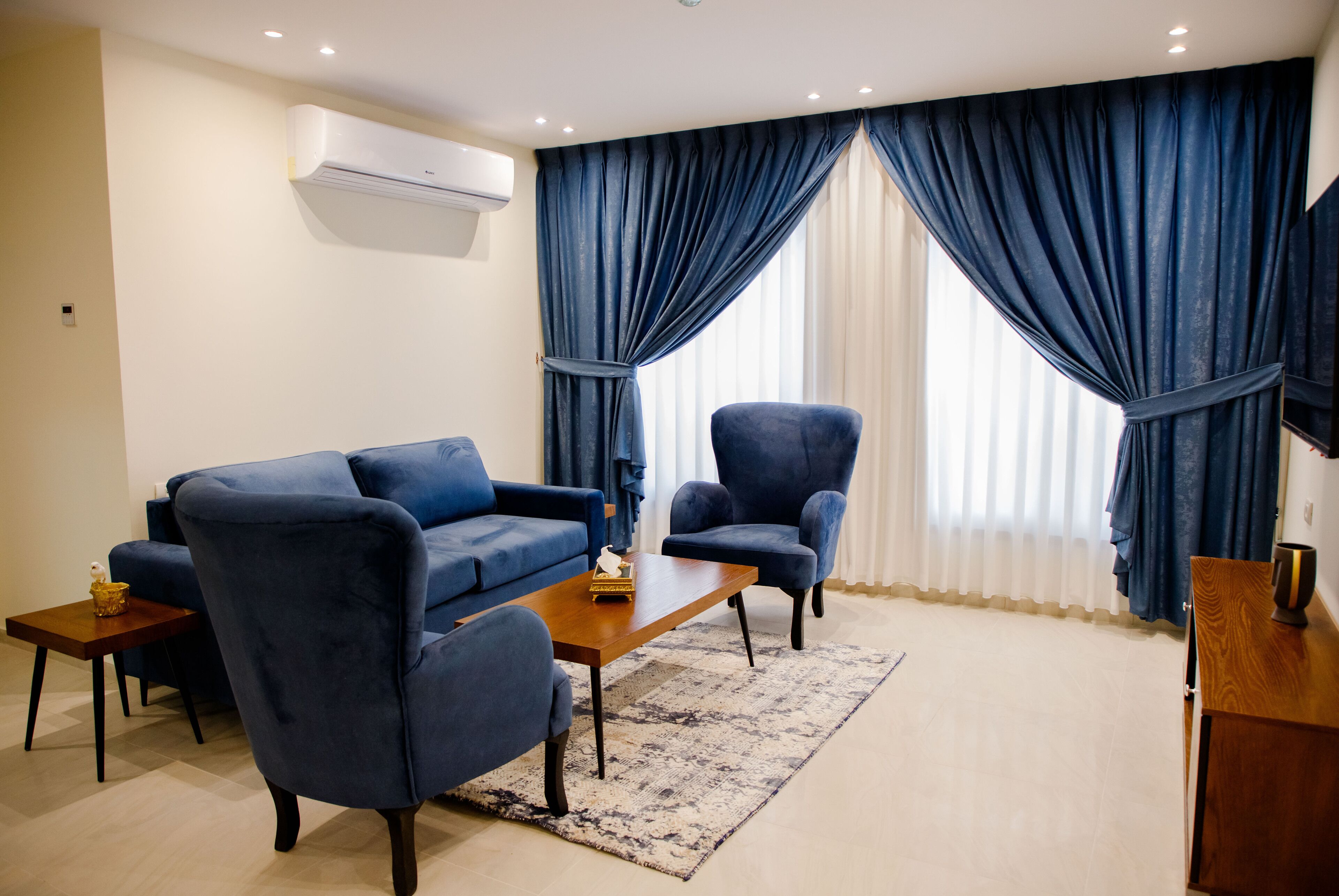 Una sala de estar con un sofá, dos sillones, una mesa de centro y una mesita auxiliar de madera.