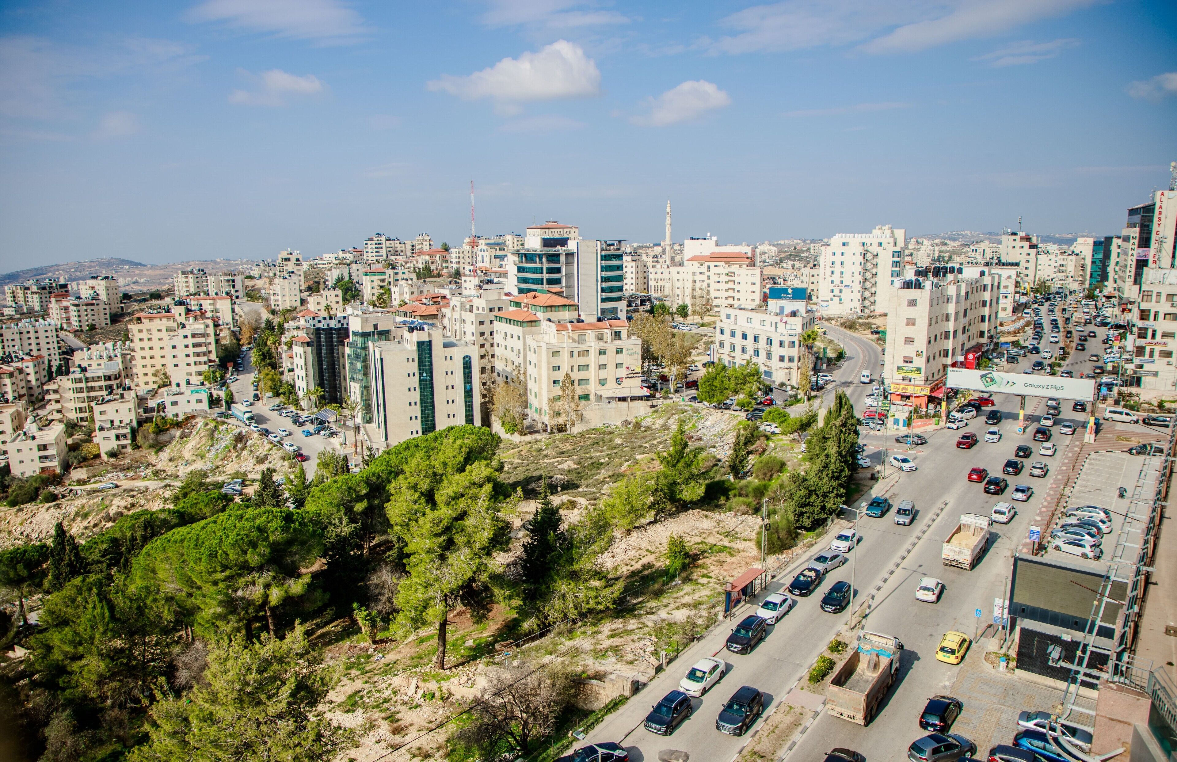 A cityscape with densely packed buildings, a busy road with cars, and a mix of residential and commercial structures.