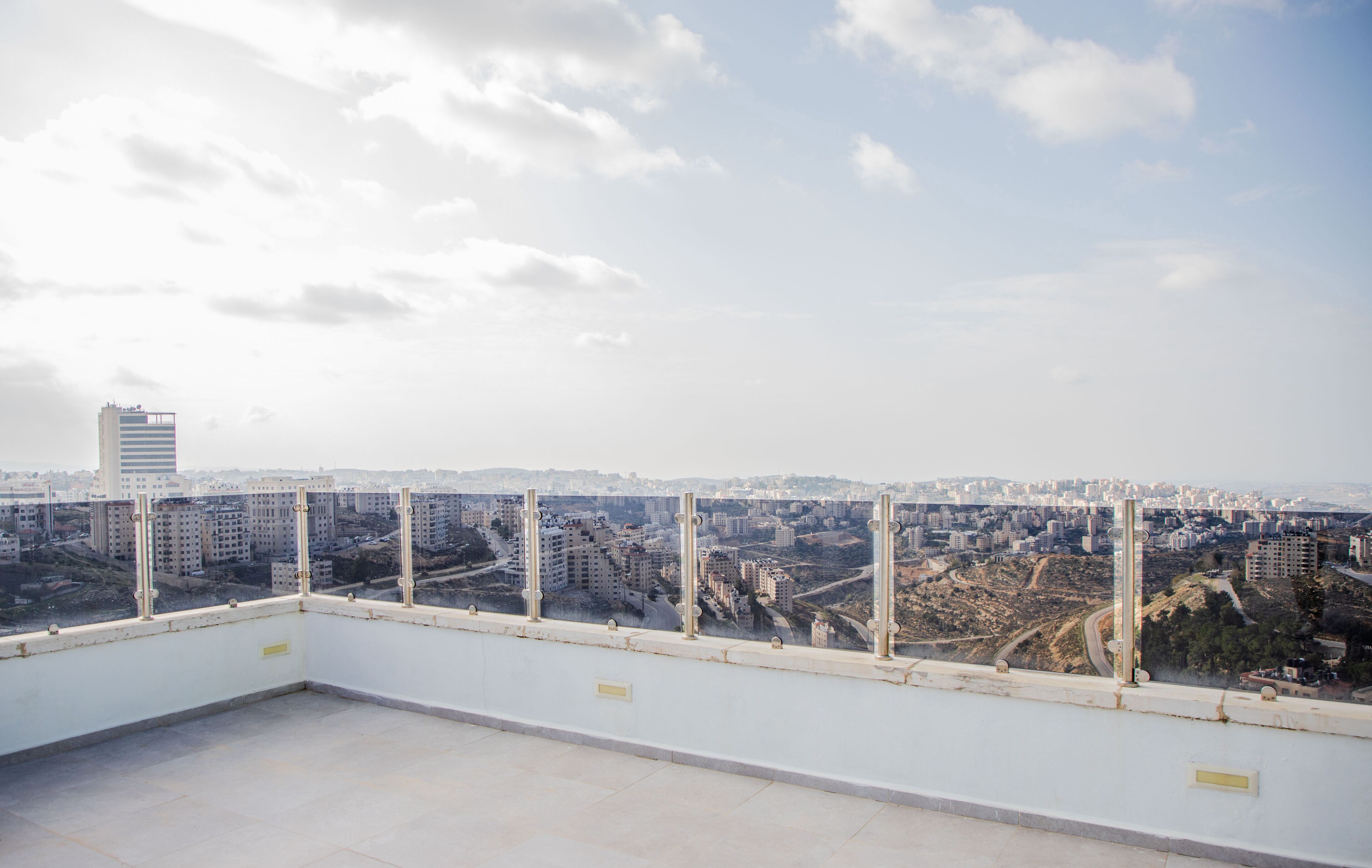 A rooftop terrace with a cityscape view, including several high-rise buildings and a clear sky.